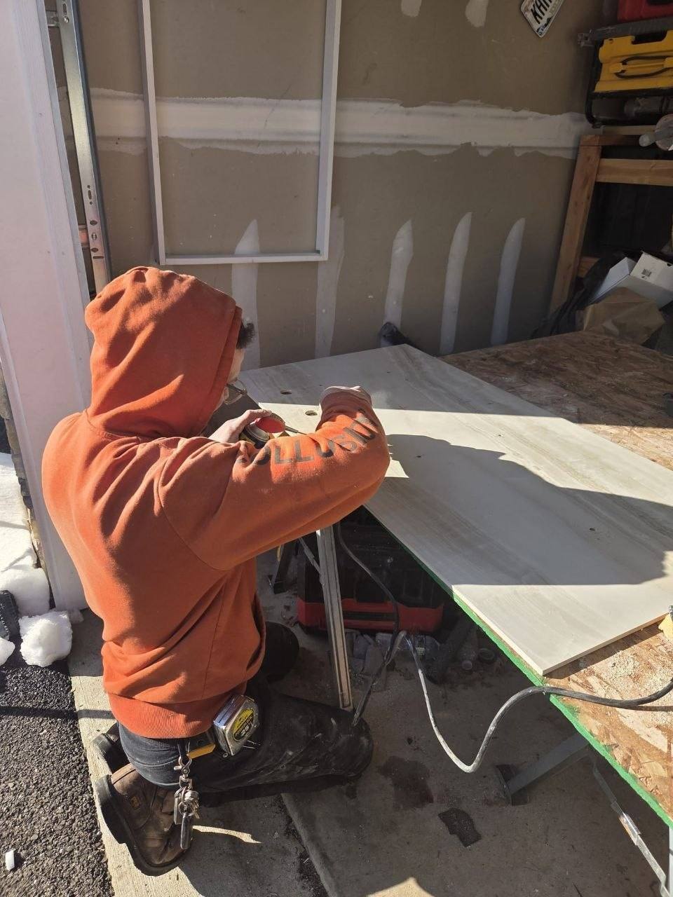 Handyman sanding a door on a work table in the garage.