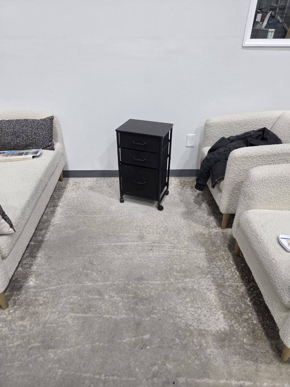 Assembled black three-drawer rolling cabinet between two sofas.