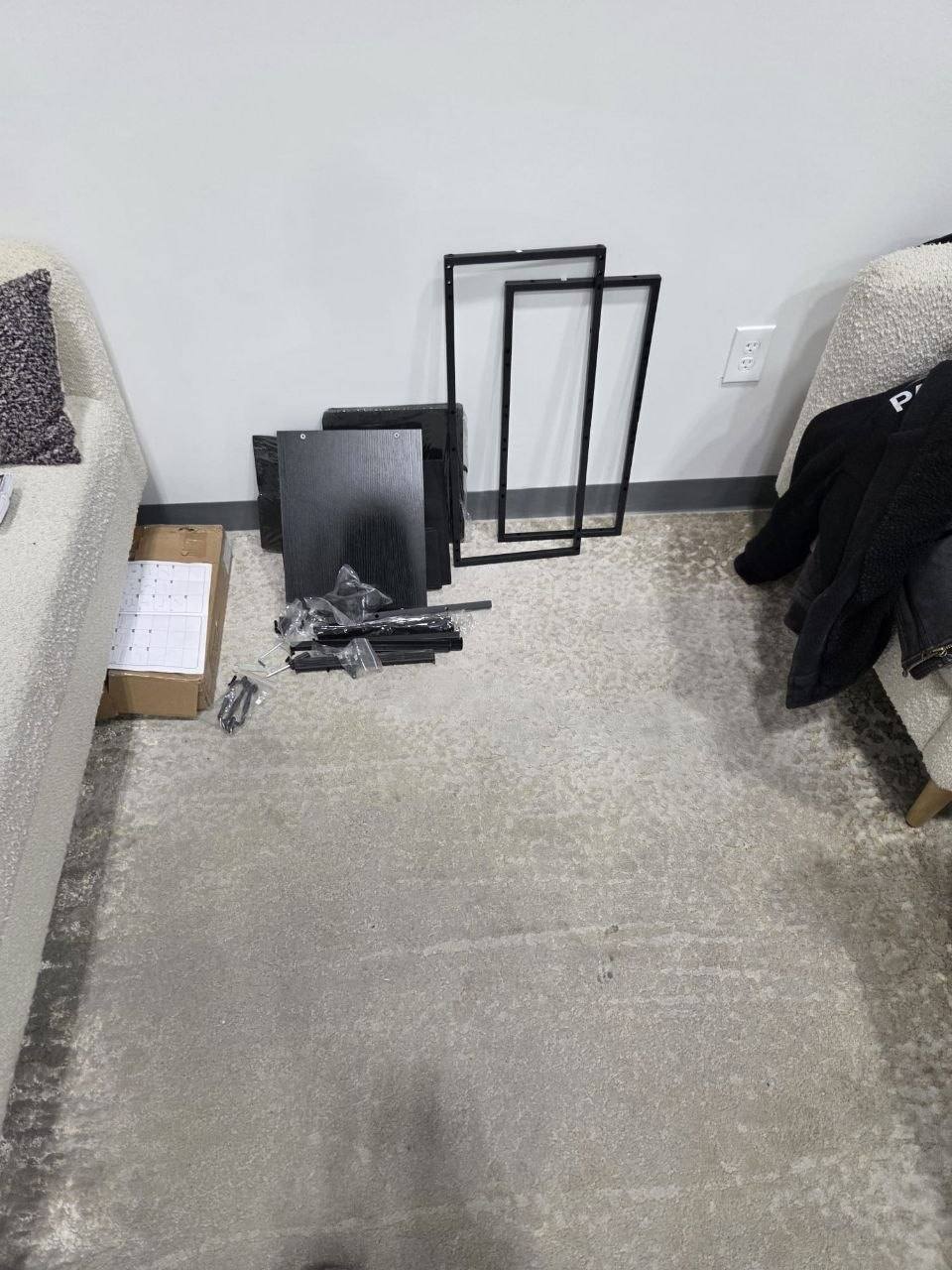 Flat-pack cabinet parts and frames on a living room rug.