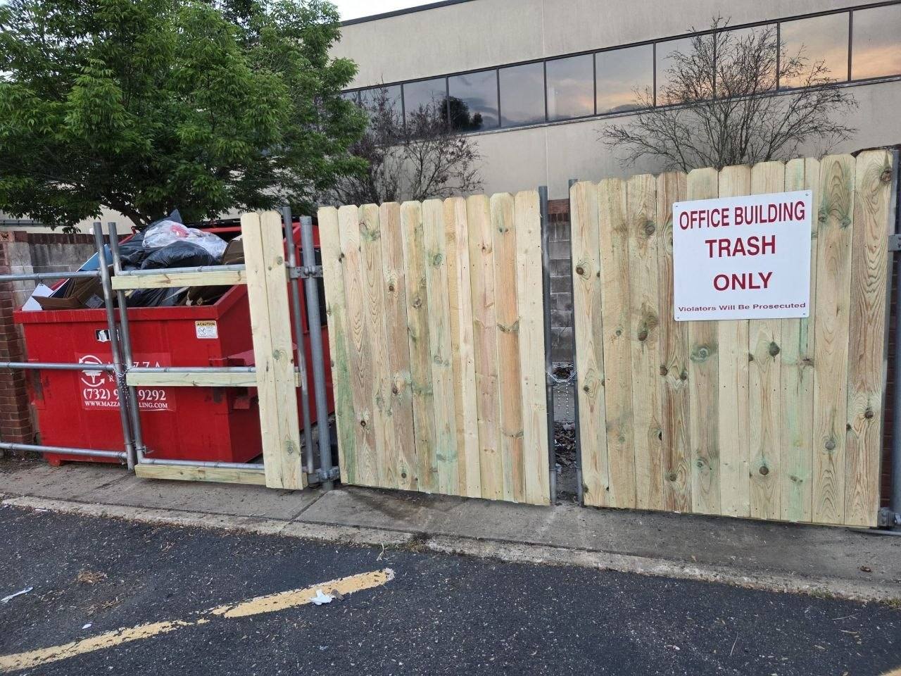Dumpster enclosure with the gate open and the dumpster visible.