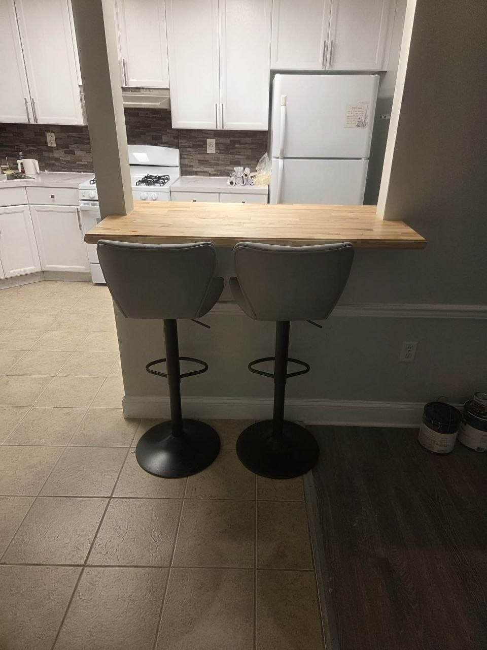 Pass-through with bar stools and paint cans still on the floor.