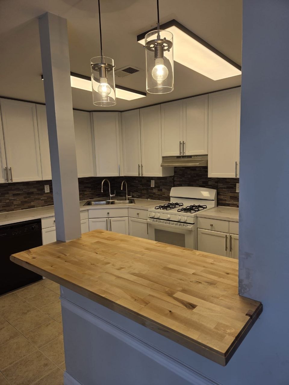 Finished pass-through with butcher-block top and glass pendants.