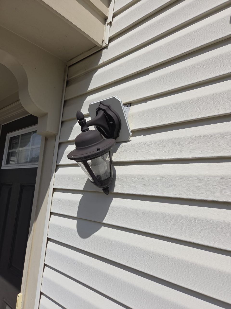 Outdoor lantern on vinyl siding with a gap at the mounting block.